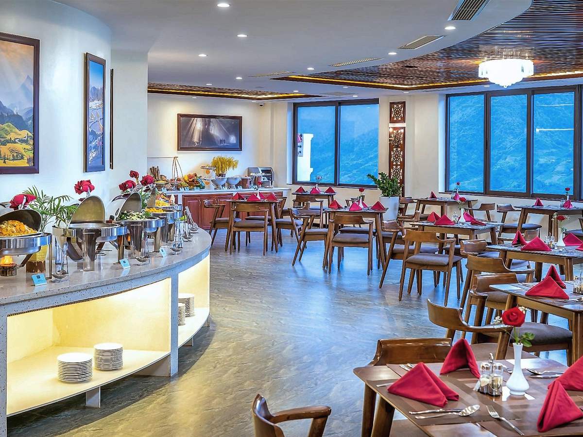 Restaurant with a long curved buffet counter, tables laid with red napkins and tall windows along one wall