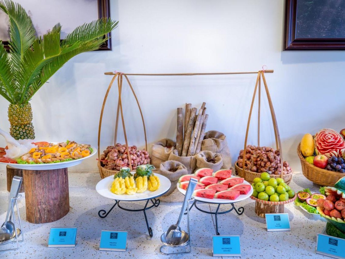 Breakfast table with carved watermelon, pineapple and tropical fruit in bamboo baskets beside a potted palm