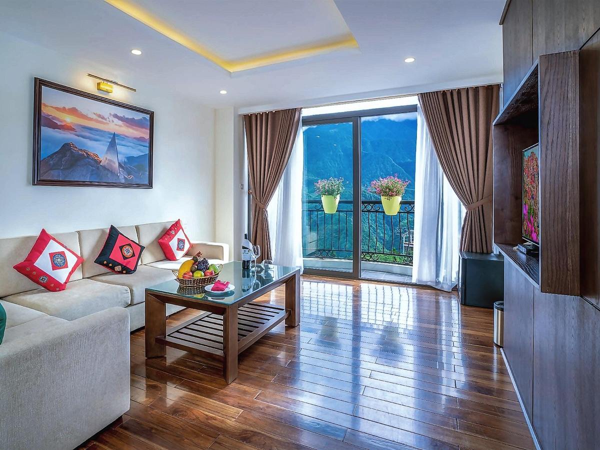 Living room with an L-shaped sofa and red cushions, a wooden floor and a glass door to a balcony with a mountain view