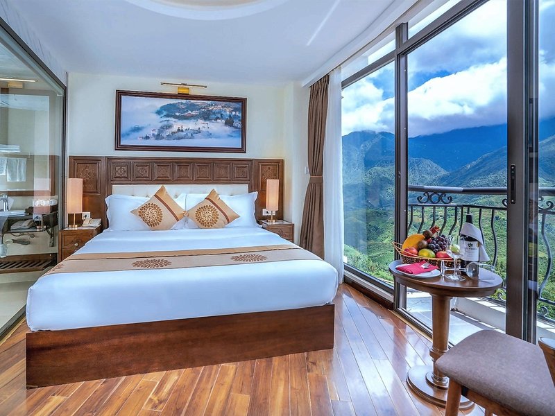 Bedroom with a wooden floor and full-height glass doors opening onto a balcony with a valley and mountain view